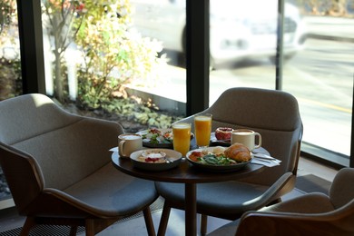 Photo of Tasty breakfast. Different meals and drinks served on wooden table in cafe