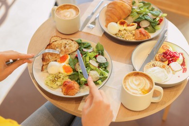 Photo of Woman having tasty breakfast in cafe, closeup