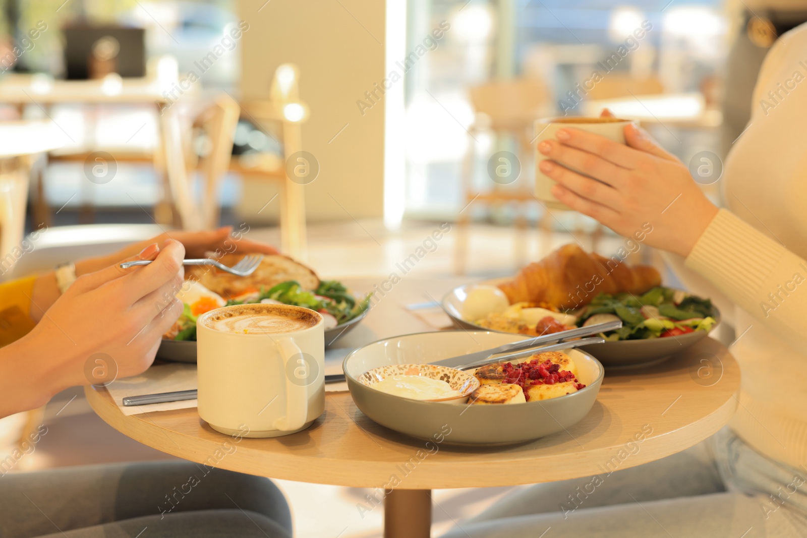 Photo of Women having tasty breakfast in cafe, closeup