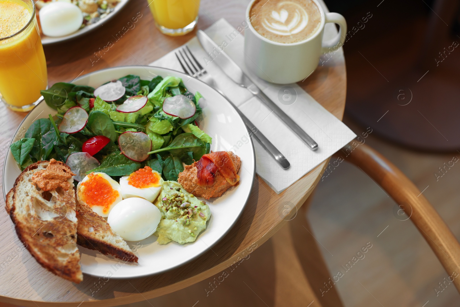 Photo of Tasty breakfast. Salad and eggs with red caviar served on wooden table in cafe, closeup