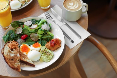 Photo of Tasty breakfast. Salad and eggs with red caviar served on wooden table in cafe, closeup