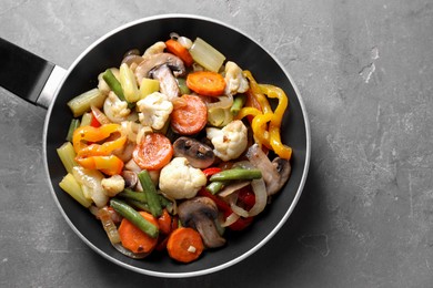 Photo of Different vegetables and mushrooms in frying pan on grey table, top view