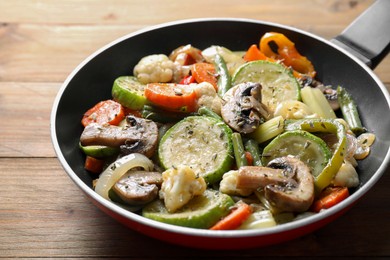 Photo of Different vegetables and mushrooms in frying pan on wooden table, closeup