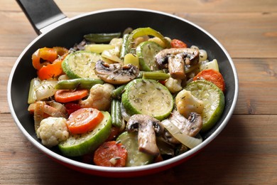 Photo of Different vegetables and mushrooms in frying pan on wooden table, closeup