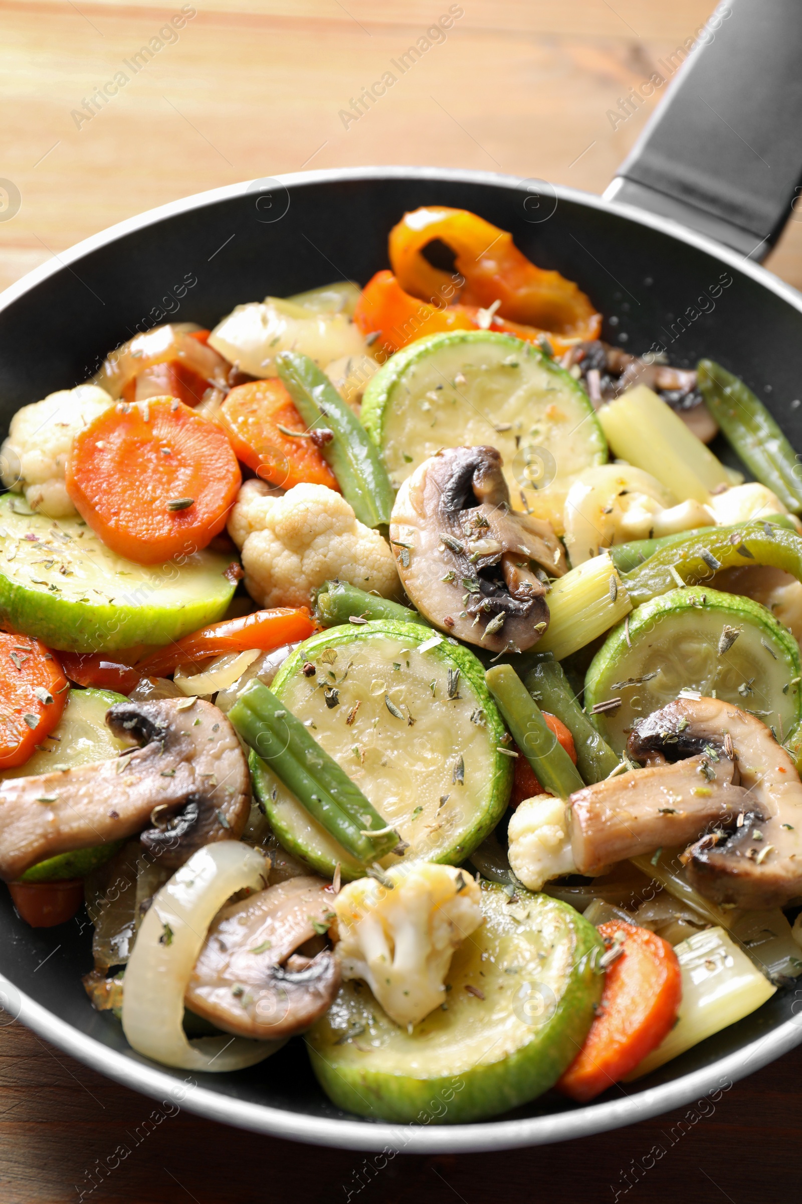 Photo of Different vegetables and mushrooms in frying pan on wooden table, closeup