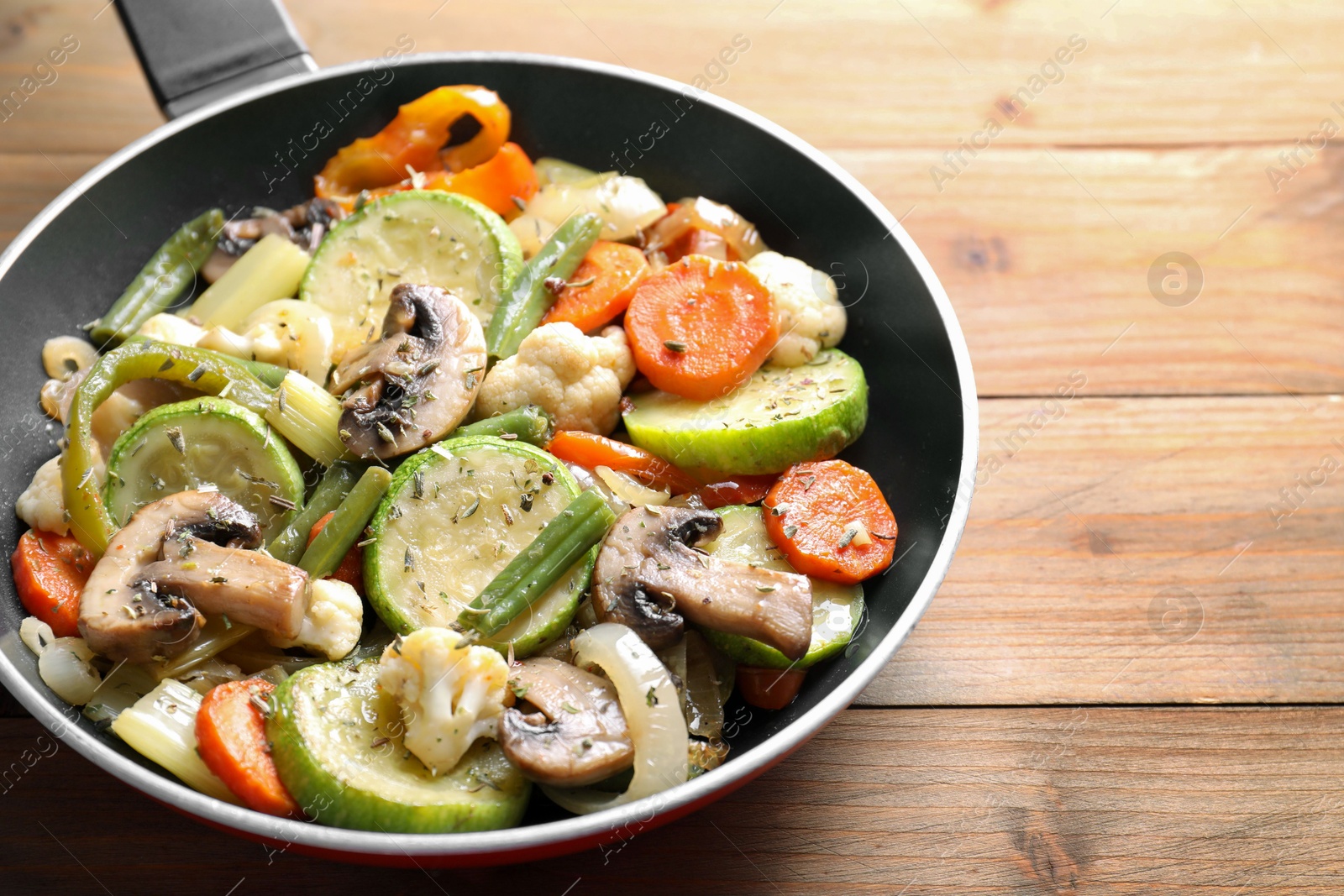 Photo of Different vegetables and mushrooms in frying pan on wooden table, closeup