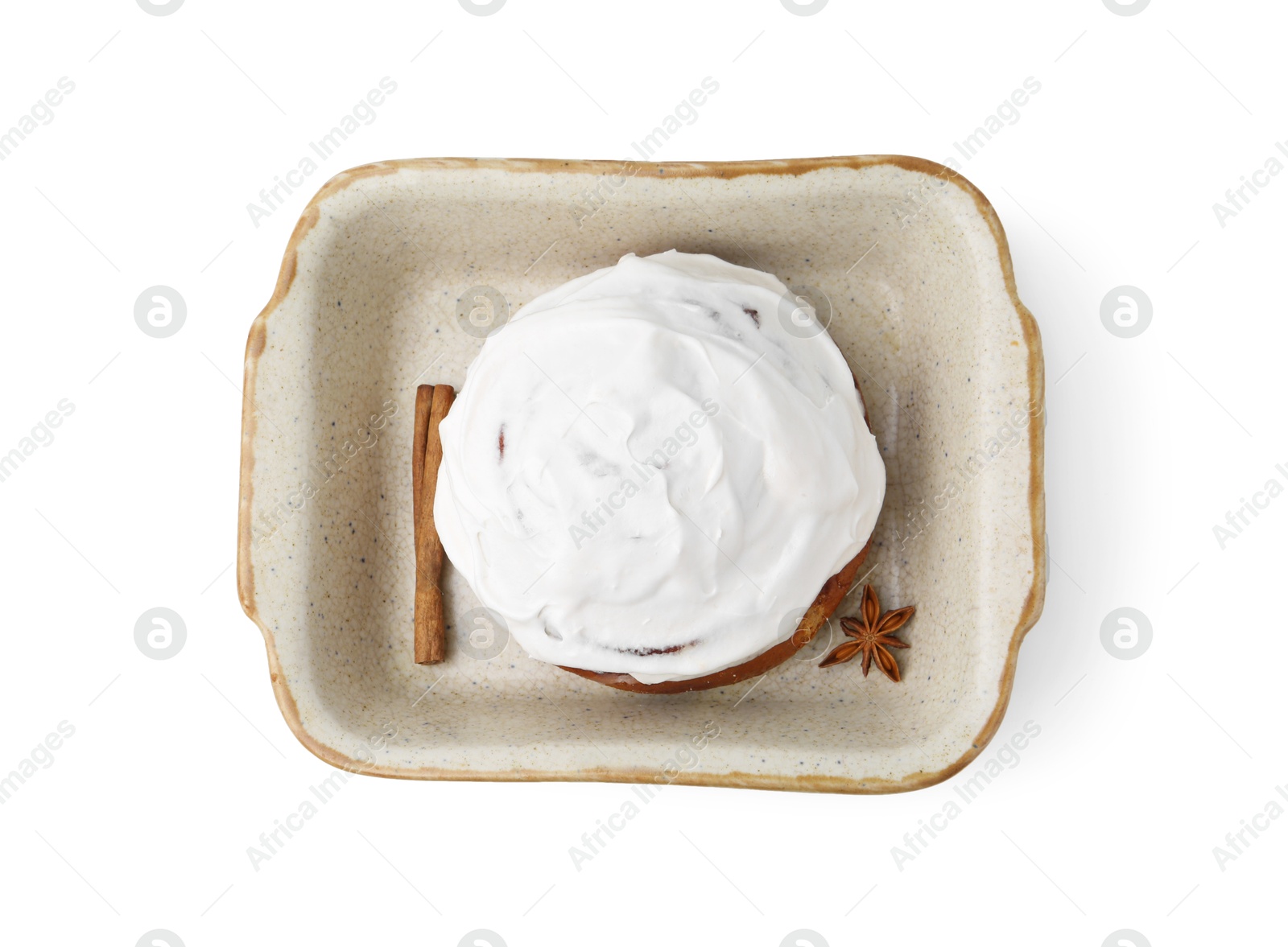 Photo of Tasty cinnamon roll with cream and spices in baking dish isolated on white, top view