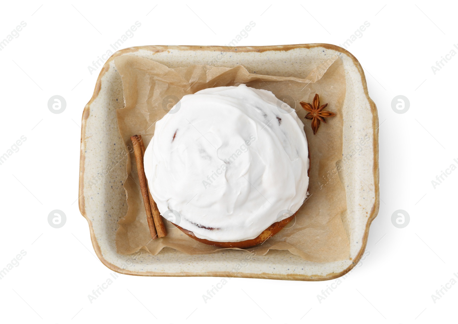 Photo of Tasty cinnamon roll with cream and spices in baking dish isolated on white, top view