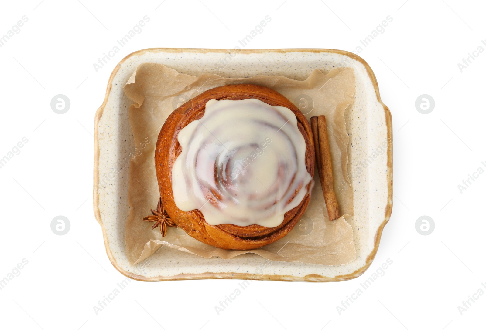 Photo of Tasty cinnamon roll with cream and spices in baking dish isolated on white, top view