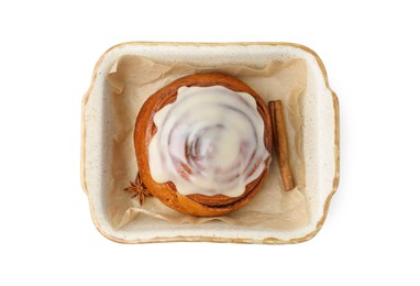 Photo of Tasty cinnamon roll with cream and spices in baking dish isolated on white, top view