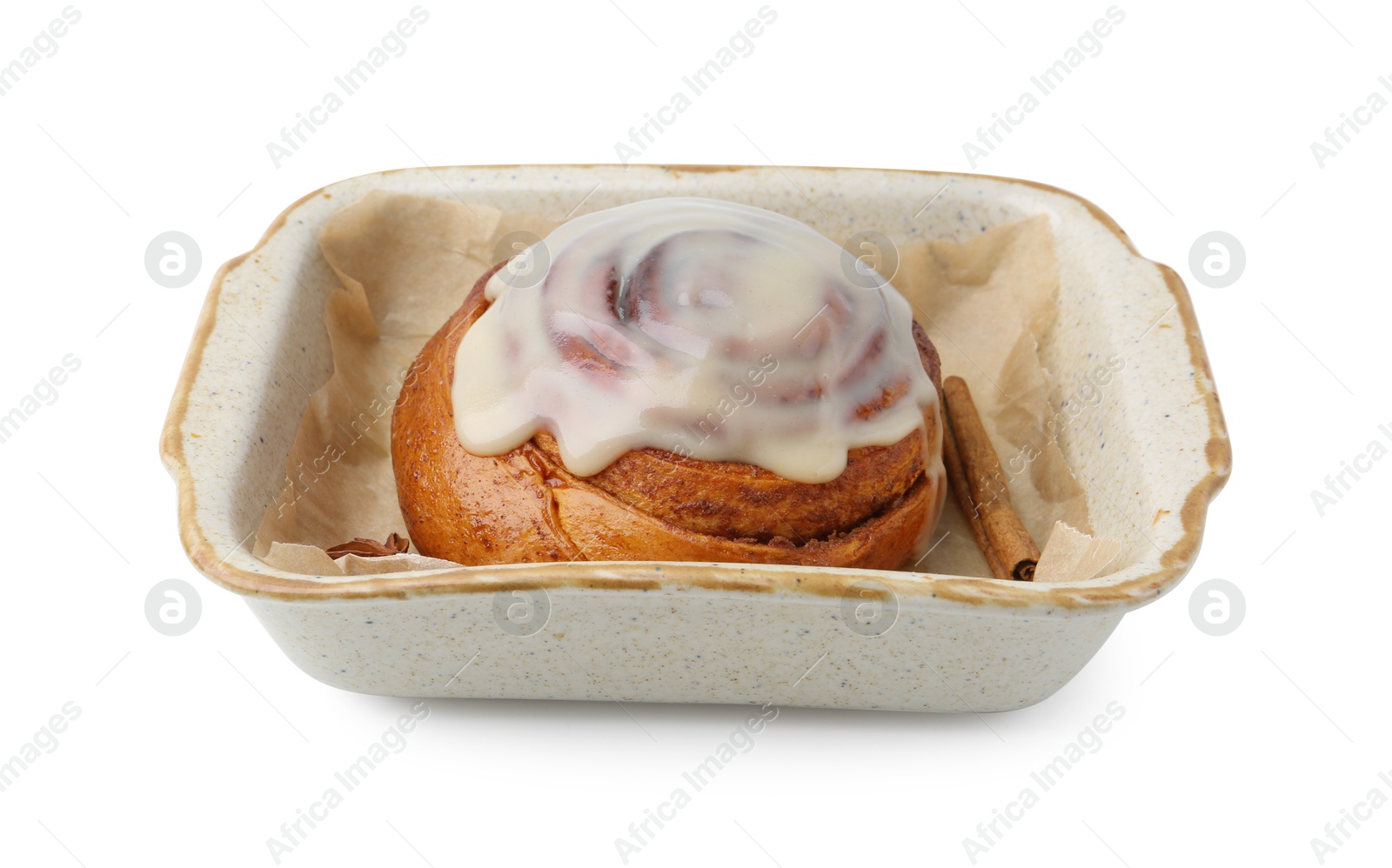 Photo of Tasty cinnamon roll with cream and spices in baking dish isolated on white