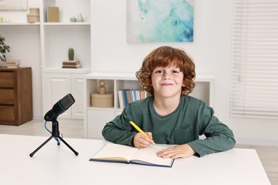 Photo of Little boy with microphone at white table indoors