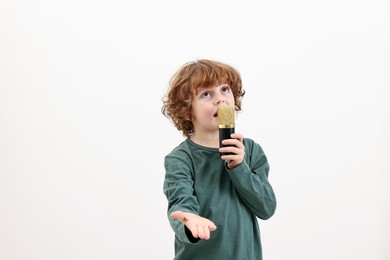 Photo of Little boy with microphone singing on white background