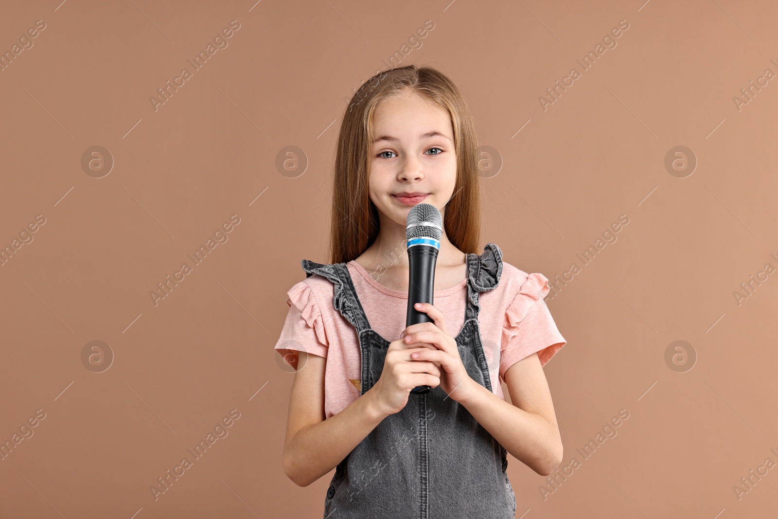 Photo of Little girl with microphone on light brown background