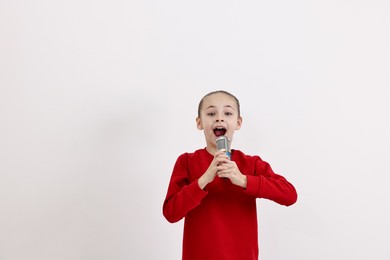 Photo of Little girl with microphone singing on white background