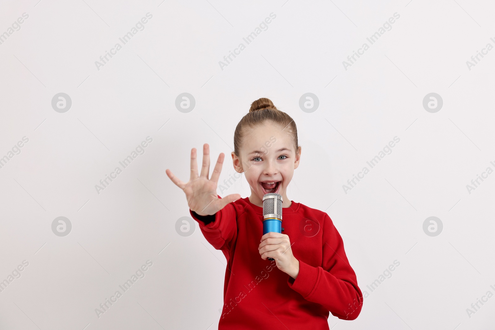 Photo of Little girl with microphone singing on white background