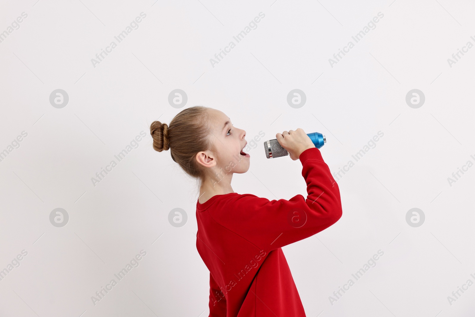 Photo of Little girl with microphone singing on white background