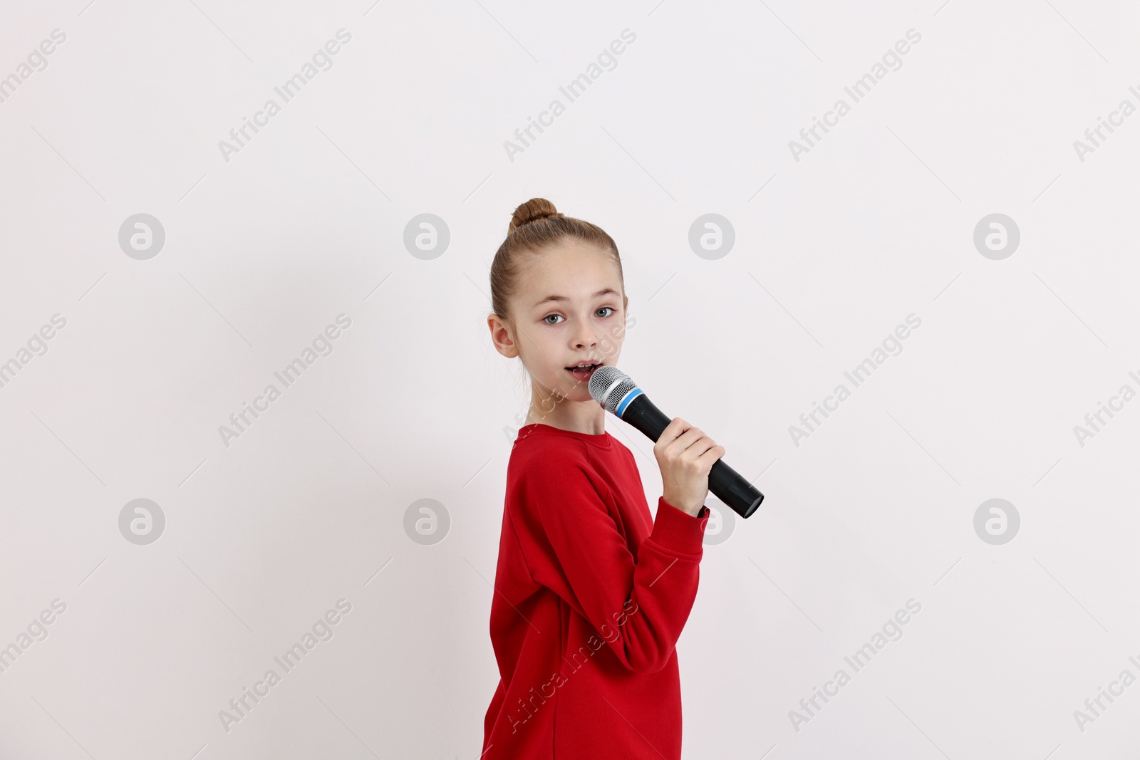 Photo of Little girl with microphone singing on white background