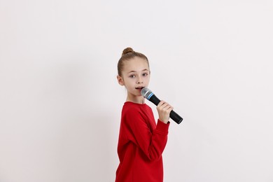 Photo of Little girl with microphone singing on white background