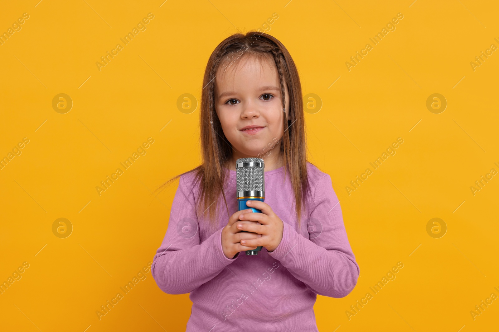 Photo of Cute girl with microphone on orange background