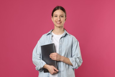 Photo of Portrait of smiling teenage girl with laptop on pink background