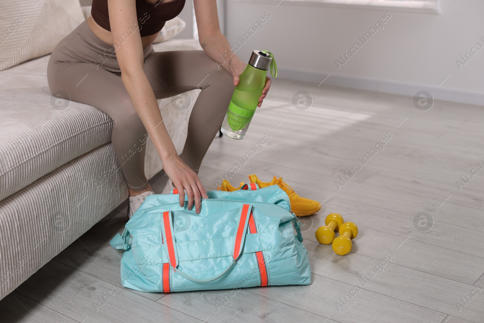 Photo of Woman packing her gym bag on sofa at home, closeup. Space for text