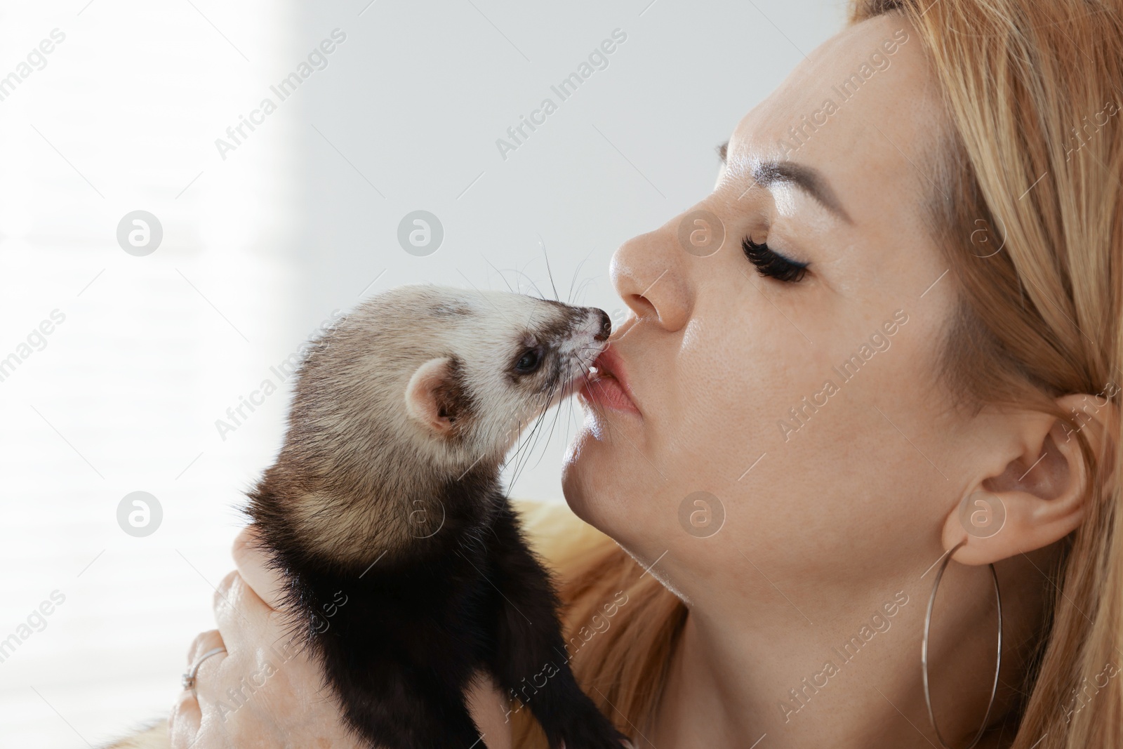 Woman with cute ferret on blurred background, closeup. Space for text Photo of Woman with cute ferret on blurred background, closeup. Space for text