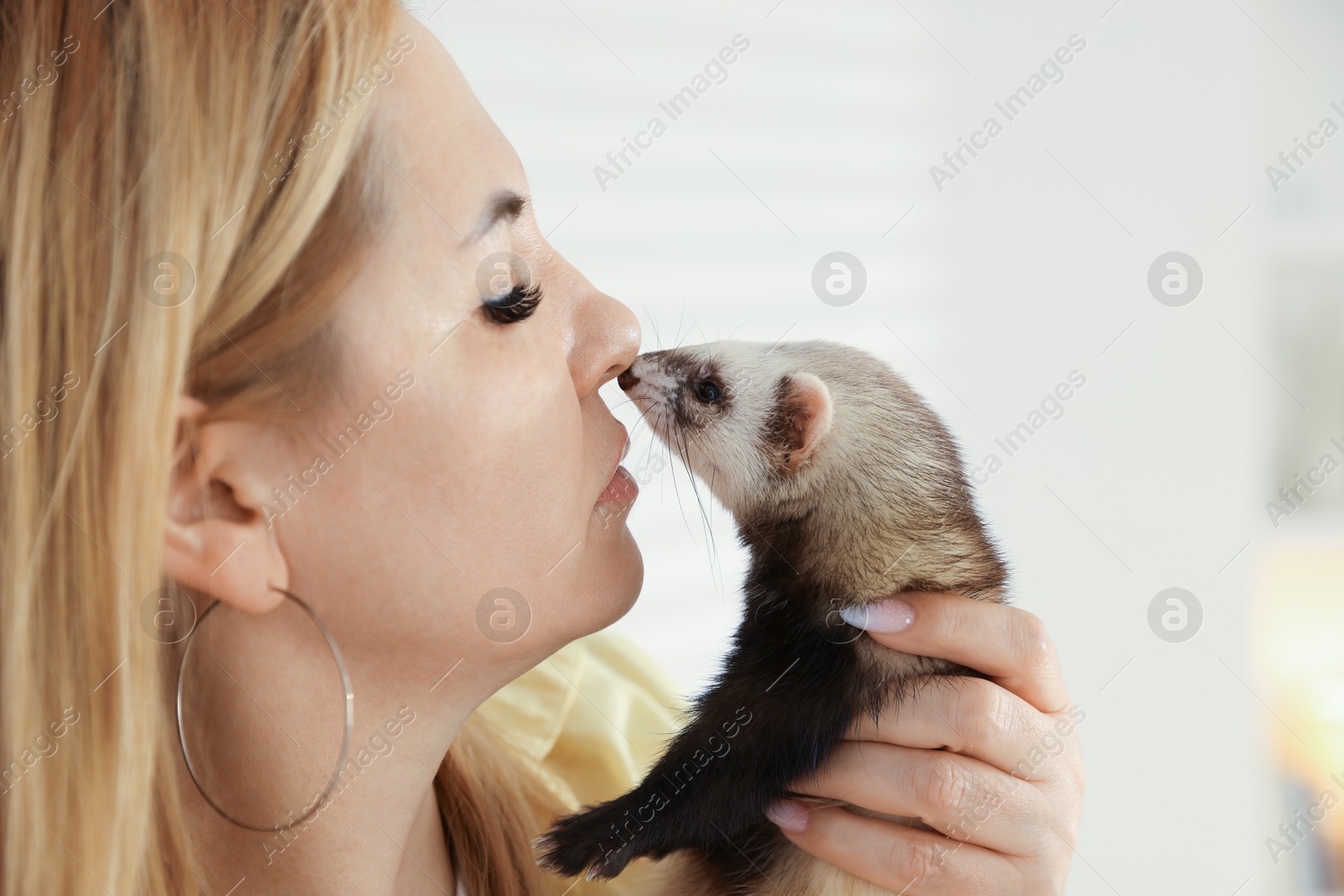 Woman with cute ferret on blurred background, closeup. Space for text Photo of Woman with cute ferret on blurred background, closeup. Space for text