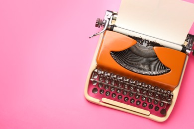 Photo of Vintage typewriter with sheet of paper on pink background, top view. Space for text