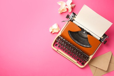 Photo of Vintage typewriter, crumpled paper and envelope on pink background, flat lay. Space for text