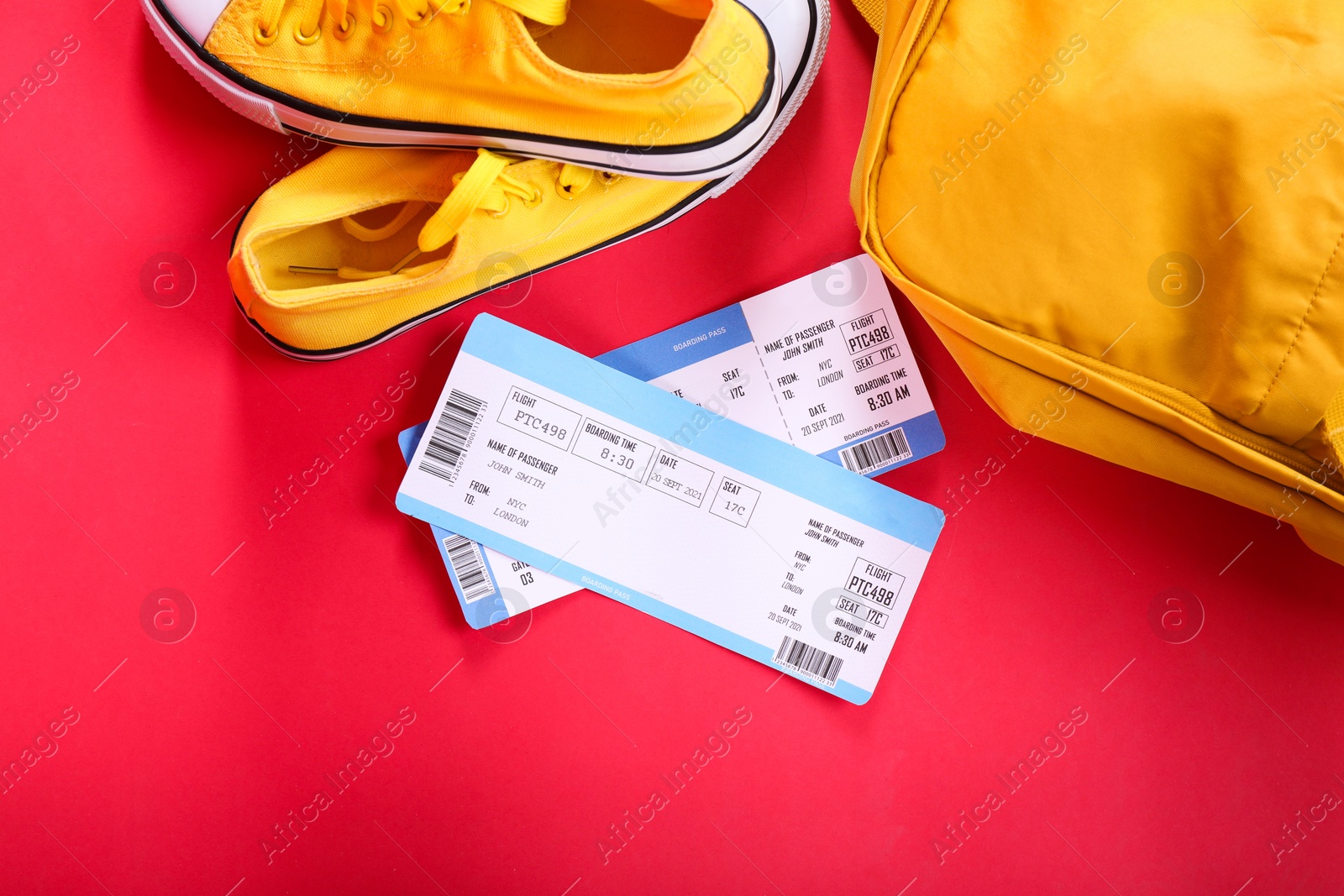 Photo of Airplane tickets, shoes and backpack on red background, flat lay. Travel abroad