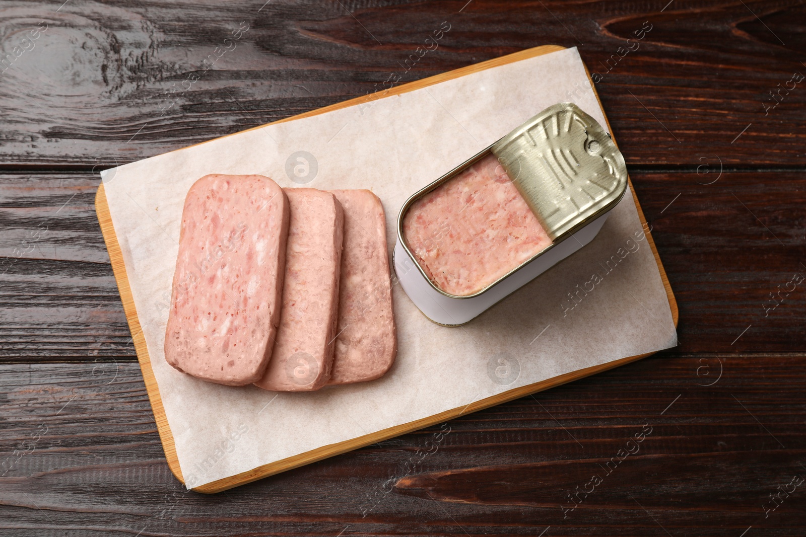 Photo of Canned meat in tin can on wooden table, top view