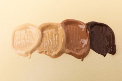 Photo of Samples of different foundations on beige background, closeup