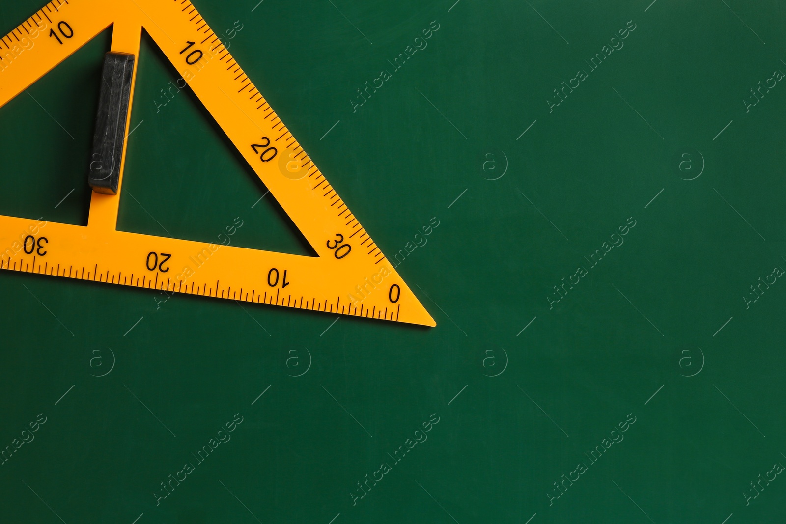 Photo of One triangle ruler on green chalkboard, top view. Space for text