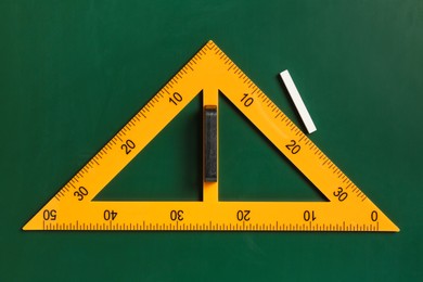 Photo of Triangle ruler and chalk on green chalkboard, top view