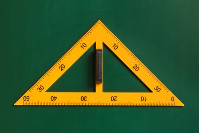 Photo of One triangle ruler on green chalkboard, top view