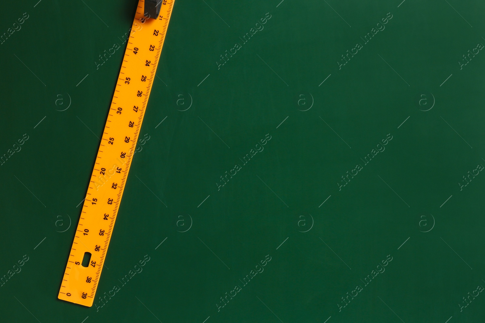 Photo of One ruler on green chalkboard, top view. Space for text