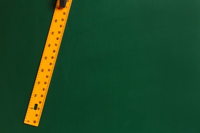 Photo of One ruler on green chalkboard, top view. Space for text