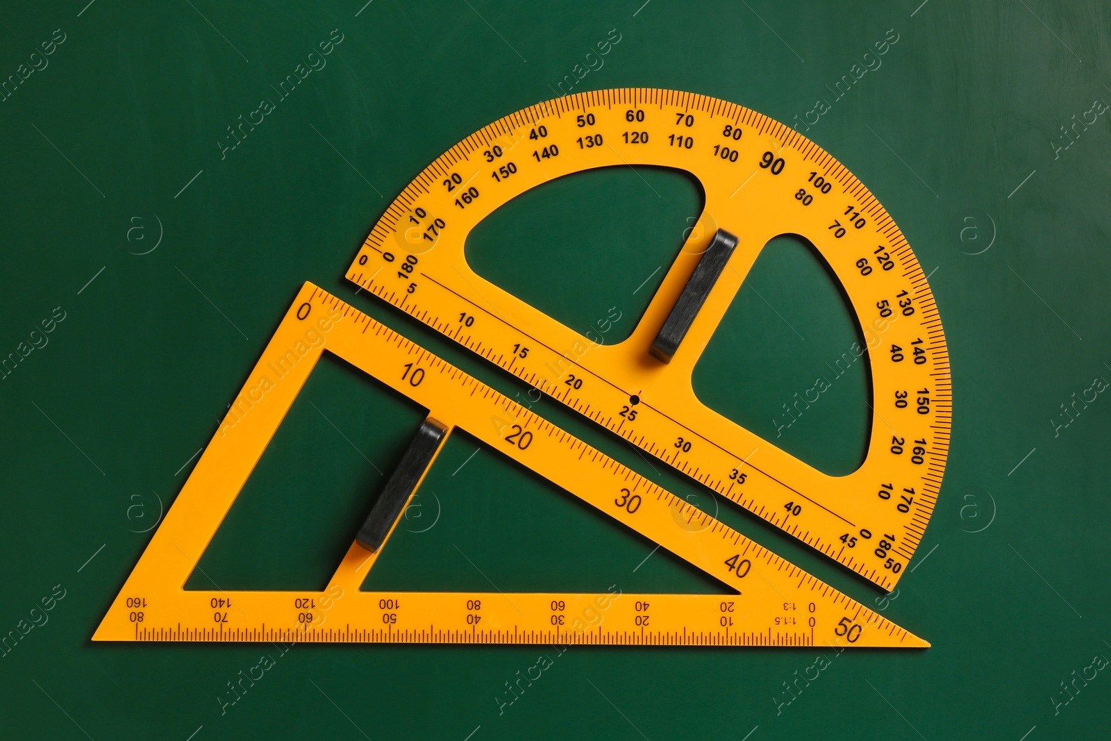 Photo of Protractor and triangle ruler on green chalkboard, top view