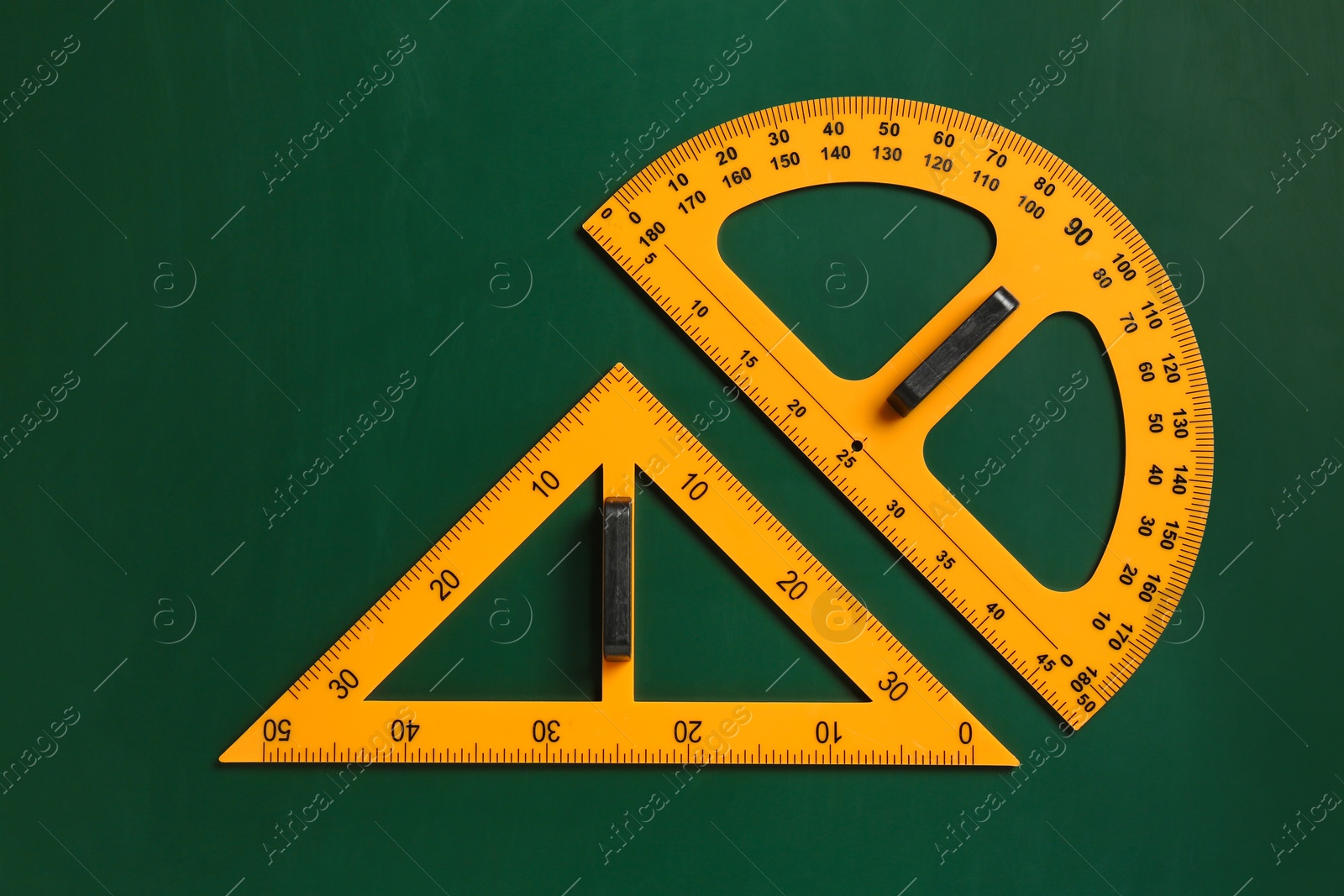 Photo of Protractor and triangle ruler on green chalkboard, top view