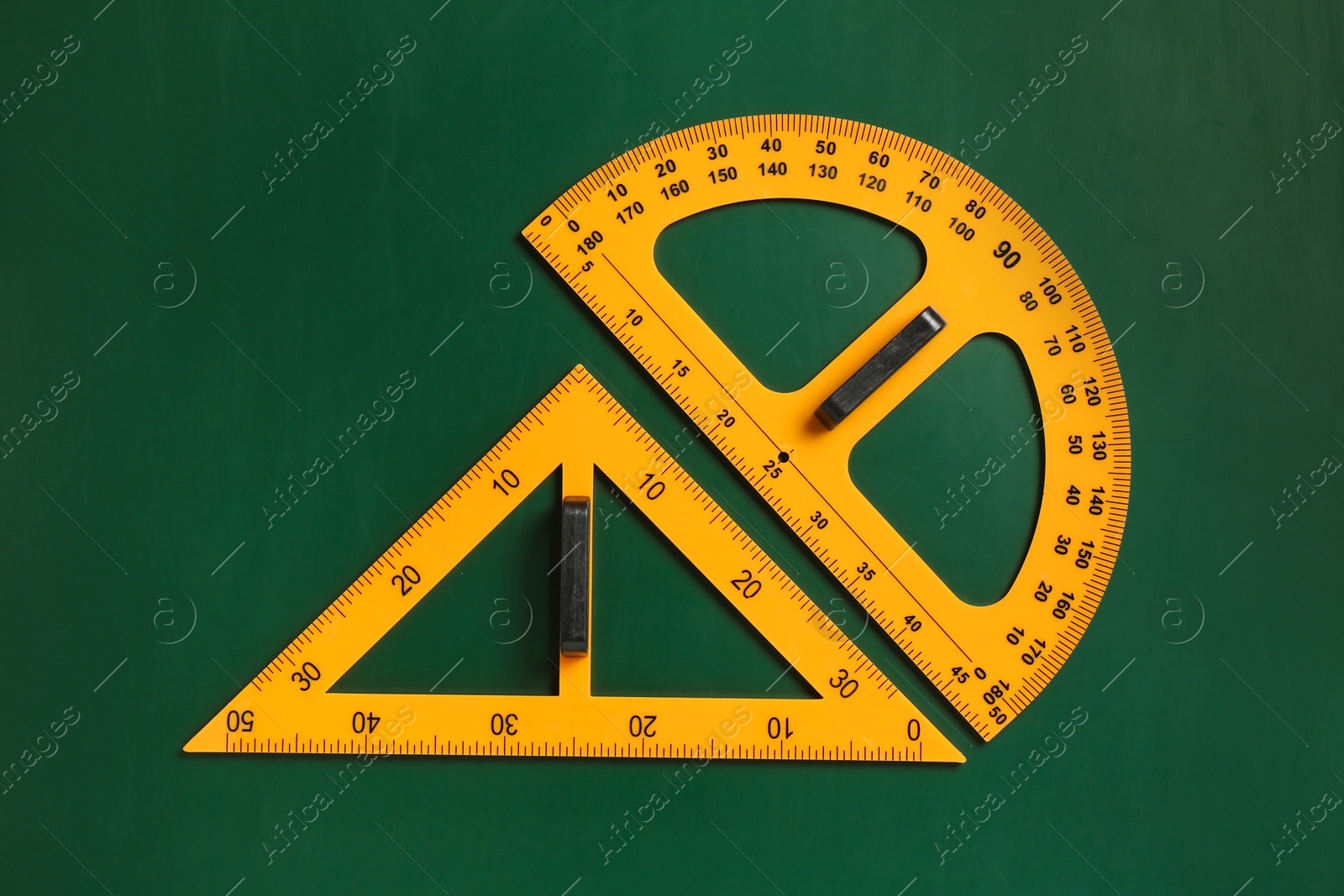 Photo of Protractor and triangle ruler on green chalkboard, top view