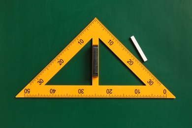 Photo of Triangle ruler and chalk on green chalkboard, top view