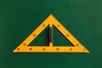 Photo of One triangle ruler on green chalkboard, top view