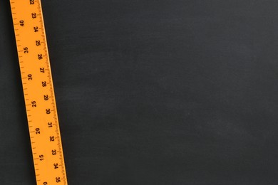 Photo of One ruler on black chalkboard, top view. Space for text