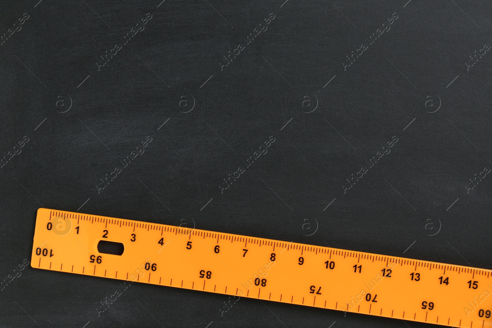 Photo of One ruler on black chalkboard, top view. Space for text