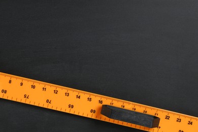 Photo of One ruler on black chalkboard, top view. Space for text