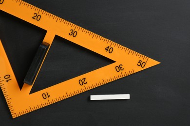 Photo of Triangle ruler and chalk on black chalkboard, top view