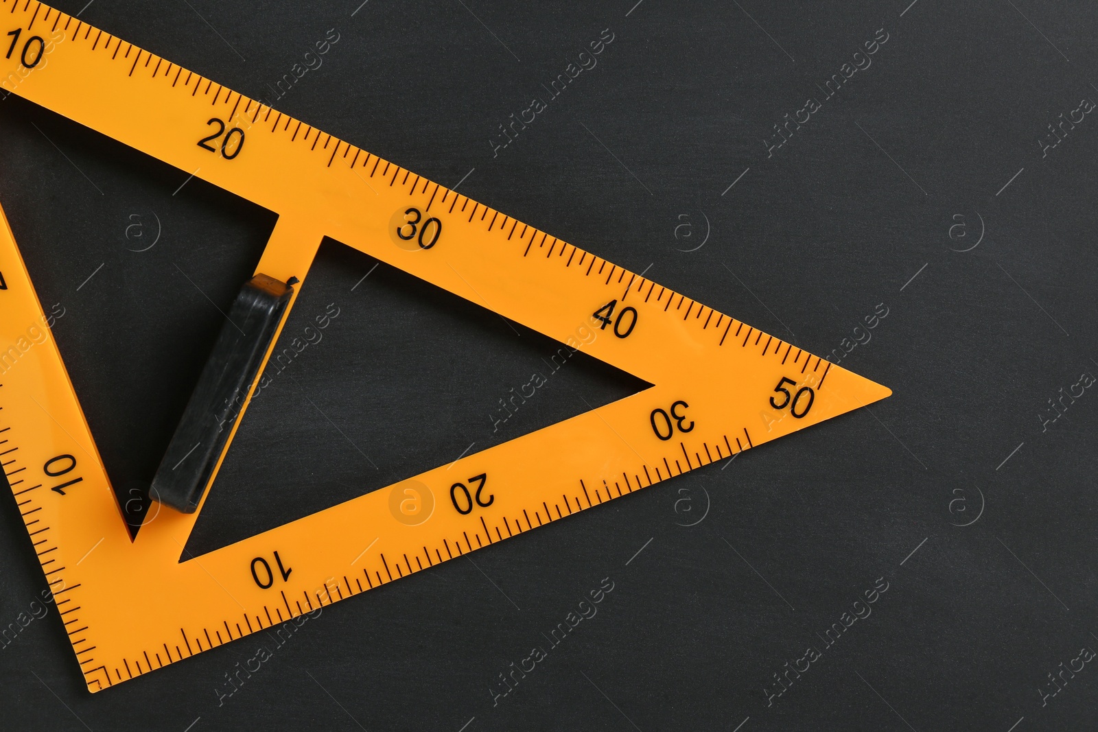 Photo of Triangle ruler on black chalkboard, top view