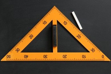 Photo of Triangle ruler and chalk on black chalkboard, top view