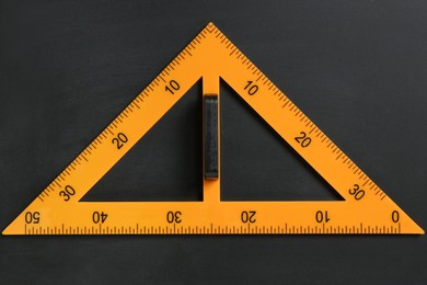 Photo of Triangle ruler on black chalkboard, top view